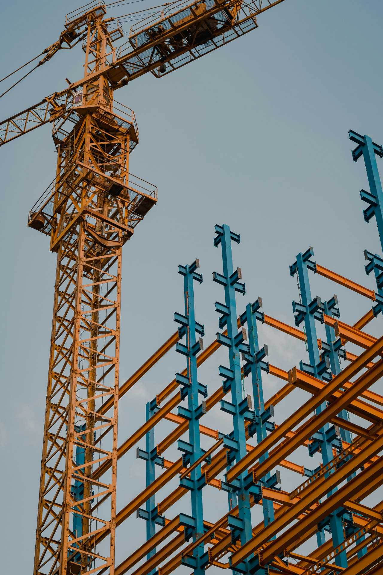 Dense blue and orange structural steel beams rising against a clear sky